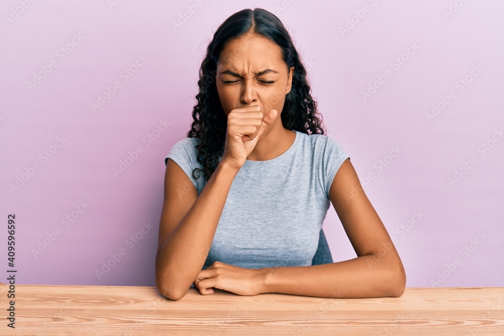 Young african american girl wearing casual clothes sitting on the table feeling unwell and coughing as symptom for cold or bronchitis. health care concept. Young african american girl wearing casual clothes sitting on the table feeling unwell and coughing as symptom for cold or bronchitis. health care concept.
