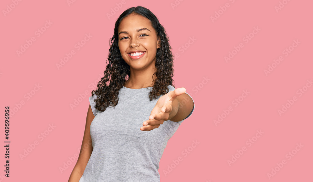 Young african american girl wearing casual clothes smiling cheerful offering palm hand giving assistance and acceptance. Young african american girl wearing casual clothes smiling cheerful offering palm hand giving assistance and acceptance.