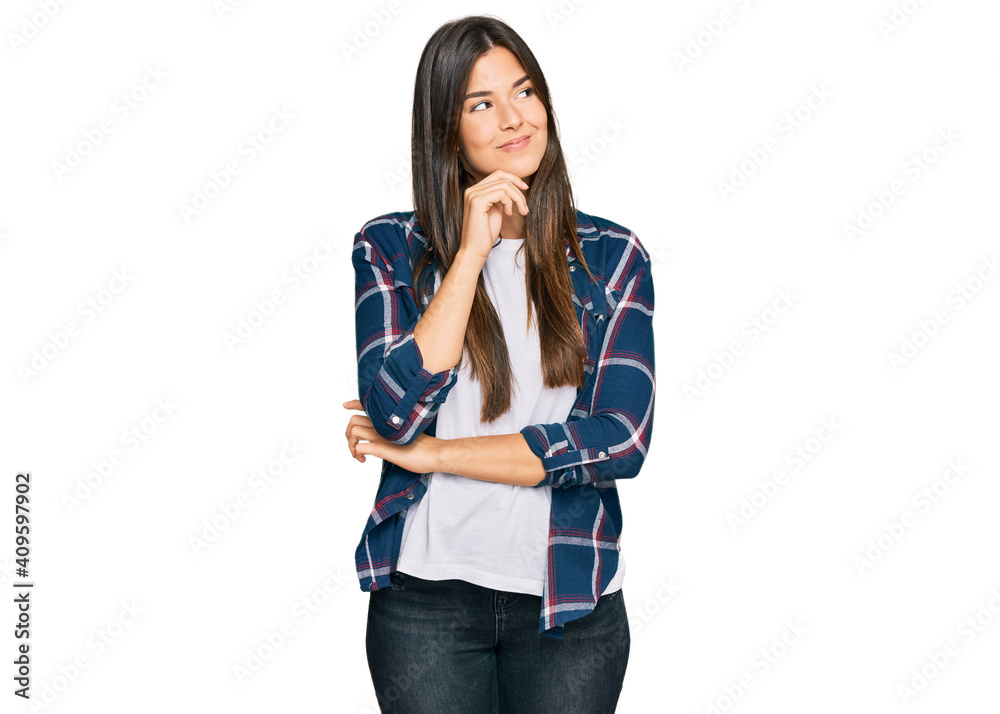 Young brunette woman wearing casual clothes serious face thinking about question with hand on chin, thoughtful about confusing idea Young brunette woman wearing casual clothes serious face thinking about question with hand on chin, thoughtful about confusing idea