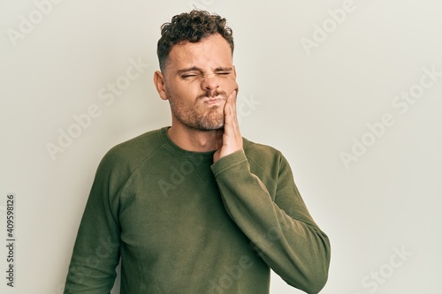 Tablou pe pânză Young hispanic man wearing casual clothes touching mouth with hand with painful expression because of toothache or dental illness on teeth