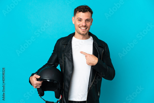 Caucasian man with a motorcycle helmet isolated on blue background with surprise facial expression