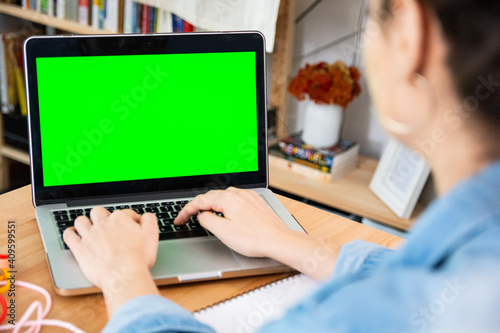 Woman entrepreneur using laptop while working in office, green screen
