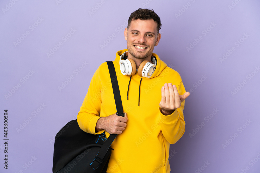 Young sport caucasian man with bag isolated purple background inviting to come with hand. Happy that you came Young sport caucasian man with bag isolated purple background inviting to come with hand. Happy that you came