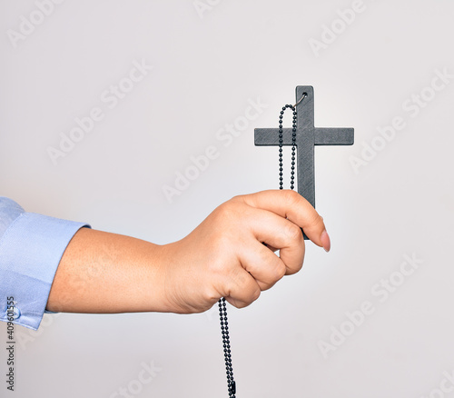 Hand of caucasian young catholic woman holding christian cross over isolated white background