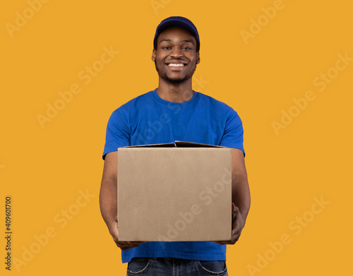 Black delivery man holding cardboard box showing it to camera photo