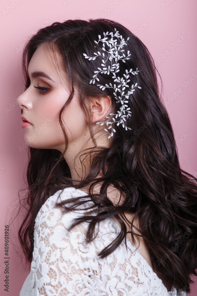 Fototapeta premium Portrait of beautiful woman wedding model with jewelry on hair looking away on pink background