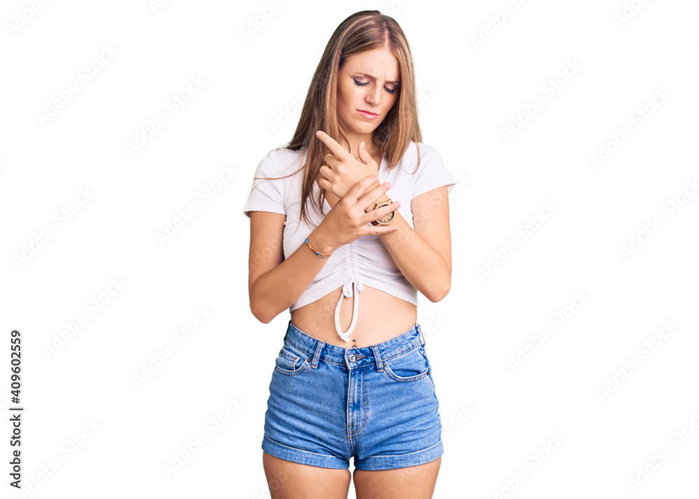 Young beautiful blonde woman wearing casual white tshirt suffering pain on hands and fingers, arthritis inflammation Young beautiful blonde woman wearing casual white tshirt suffering pain on hands and fingers, arthritis inflammation
