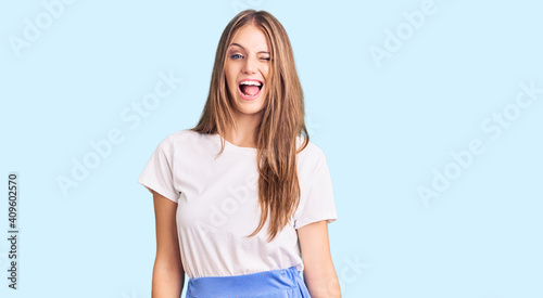 Young beautiful blonde woman wearing summer style winking looking at the camera with sexy expression, cheerful and happy face.