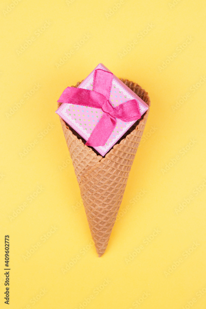Small gift box in ice cream cone on bright yellow background. Minimal Valentines day concept. Small gift box in ice cream cone on bright yellow background. Minimal Valentines day concept.