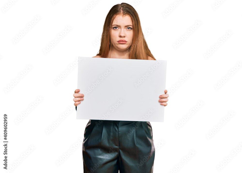 Young beautiful redhead woman holding blank empty banner thinking attitude and sober expression looking self confident Young beautiful redhead woman holding blank empty banner thinking attitude and sober expression looking self confident