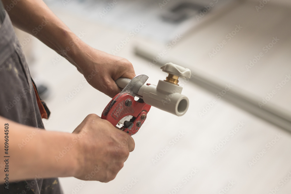 Close-up of hand with yellow scissors cut pipes for heating or water supply