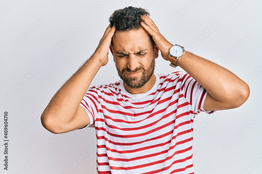 Handsome man with beard wearing casual clothes suffering from headache desperate and stressed because pain and migraine. hands on head.