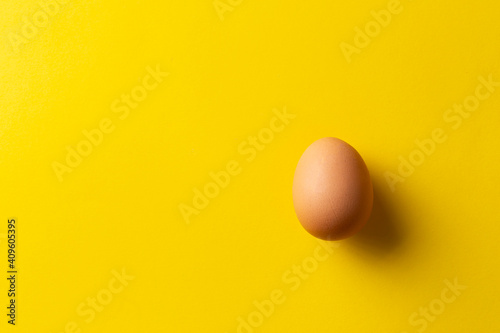 Сhicken egg isolated on yellow. Top view with copy space.