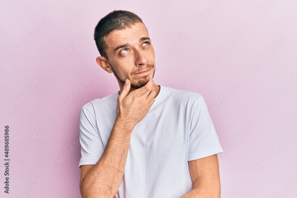 Hispanic young man wearing casual white t shirt thinking concentrated about doubt with finger on chin and looking up wondering Hispanic young man wearing casual white t shirt thinking concentrated about doubt with finger on chin and looking up wondering