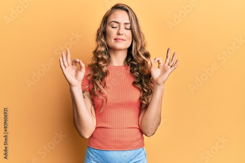 Young blonde girl wearing casual clothes relax and smiling with eyes closed doing meditation gesture with fingers. yoga concept.