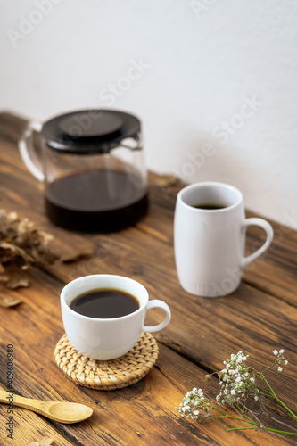 Zwei weiße Tassen mit Kaffee und eine Glaskanne auf einem rustikalen Holz Tisch. Retro, Frühstück, Zuhause.