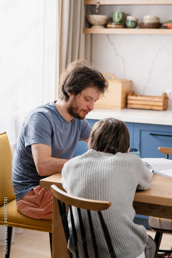 Teenager boy doing school lessons at home. Dad helping solve difficult math problems. Problems and difficulties of home education Teenager boy doing school lessons at home. Dad helping solve difficult math problems. Problems and difficulties of home education