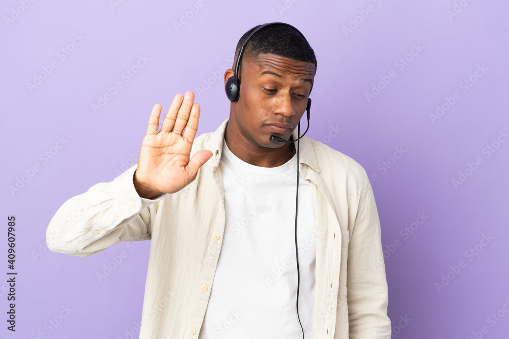 Telemarketer latin man working with a headset isolated on purple background making stop gesture and disappointed Telemarketer latin man working with a headset isolated on purple background making stop gesture and disappointed