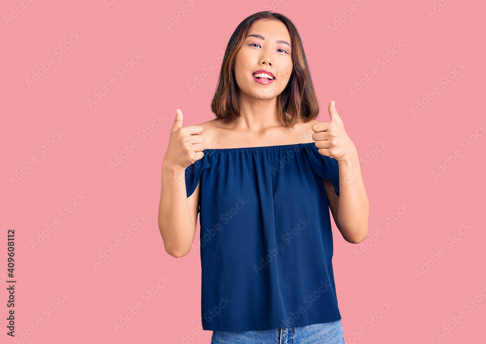 Young beautiful chinese girl wearing casual clothes success sign doing positive gesture with hand, thumbs up smiling and happy. cheerful expression and winner gesture. Young beautiful chinese girl wearing casual clothes success sign doing positive gesture with hand, thumbs up smiling and happy. cheerful expression and winner gesture.