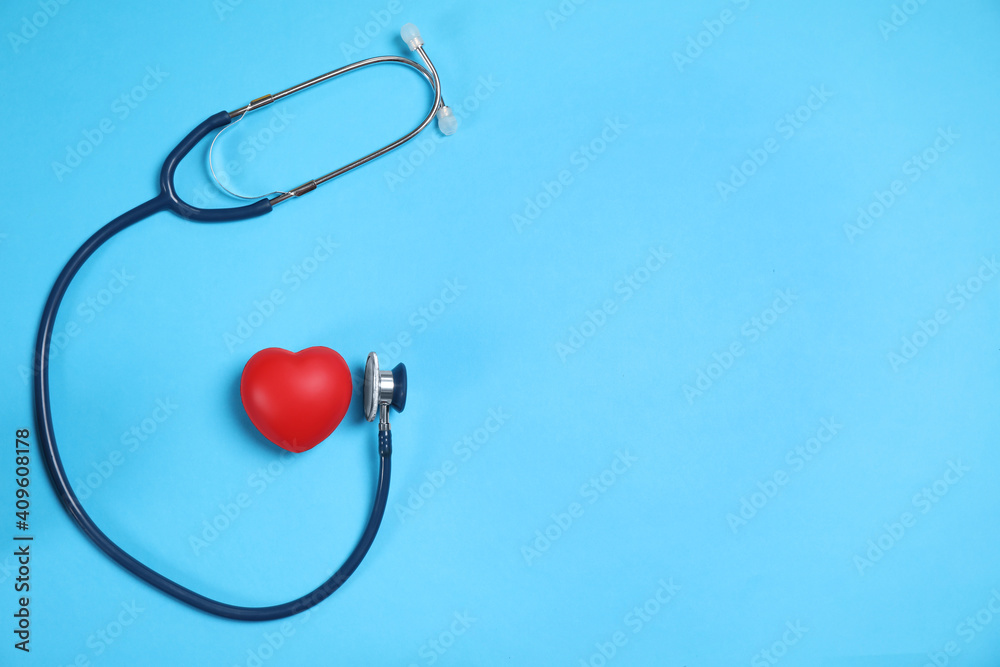 Stethoscope and red heart on light blue background, flat lay. Space for text Stethoscope and red heart on light blue background, flat lay. Space for text