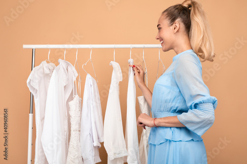Young woman choosing clothes standing near rack