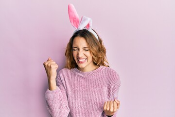 Young caucasian woman wearing cute easter bunny ears celebrating surprised and amazed for success with arms raised and eyes closed