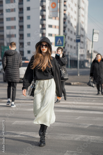 Young lady with black hoodie, sunglasses, crossing street