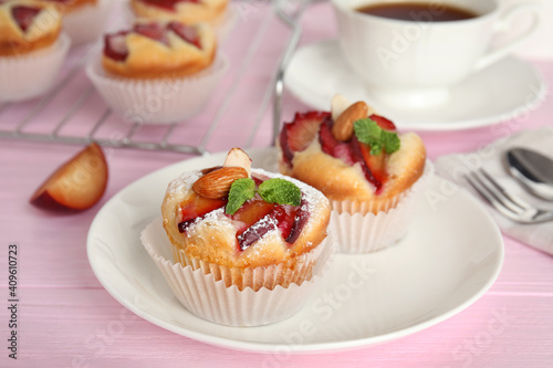 Delicious cupcakes with plums on pink wooden table, closeup