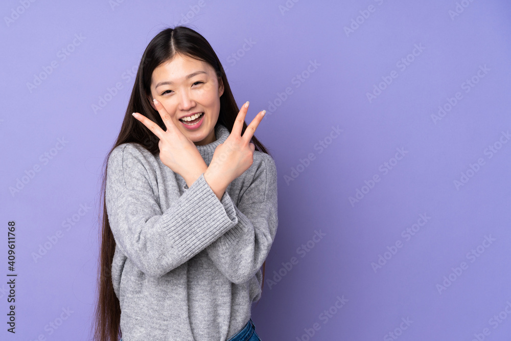 Young asian woman over isolated background smiling and showing victory sign Young asian woman over isolated background smiling and showing victory sign