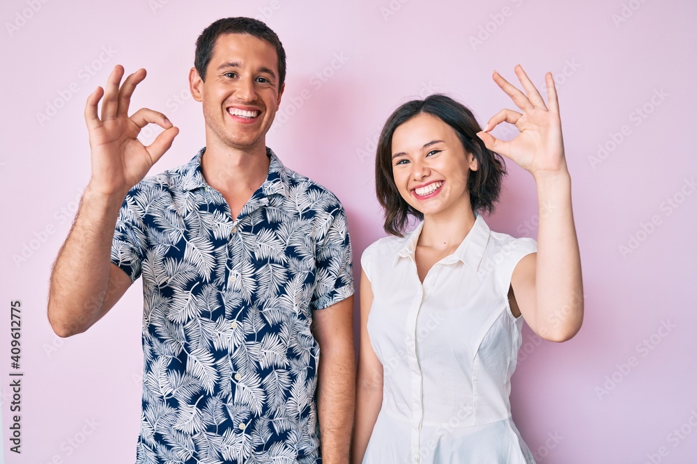Beautiful couple wearing casual clothes smiling positive doing ok sign with hand and fingers. successful expression. Beautiful couple wearing casual clothes smiling positive doing ok sign with hand and fingers. successful expression.