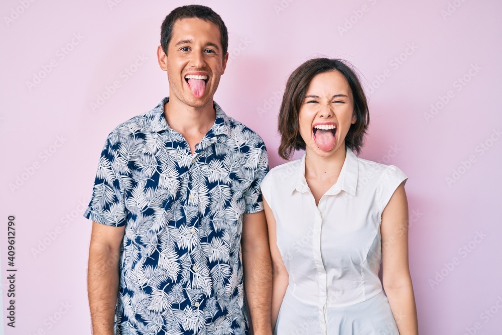 Beautiful couple wearing casual clothes sticking tongue out happy with funny expression. emotion concept. Beautiful couple wearing casual clothes sticking tongue out happy with funny expression. emotion concept.