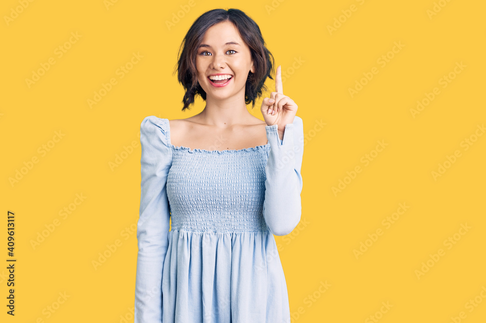 Young beautiful girl wearing casual clothes pointing finger up with successful idea. exited and happy. number one. Young beautiful girl wearing casual clothes pointing finger up with successful idea. exited and happy. number one.