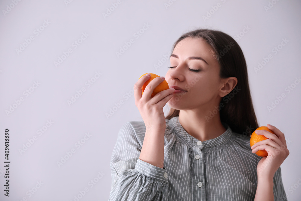 Woman with fresh tangerines on light grey background. Space for text Woman with fresh tangerines on light grey background. Space for text