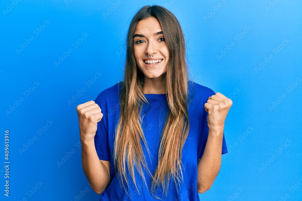 Fototapeta premium Young hispanic woman wearing casual clothes celebrating surprised and amazed for success with arms raised and open eyes. winner concept.