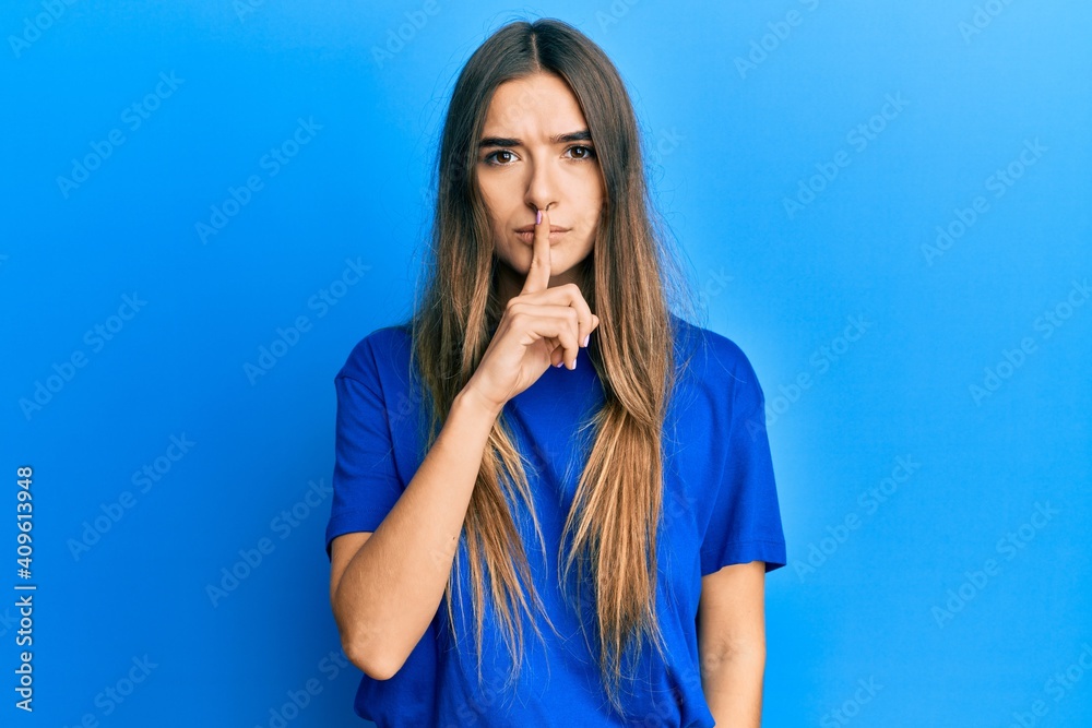 Young hispanic woman wearing casual clothes asking to be quiet with finger on lips. silence and secret concept.