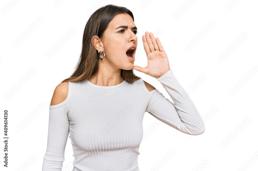 Young hispanic woman wearing casual clothes shouting and screaming loud to side with hand on mouth. communication concept. Young hispanic woman wearing casual clothes shouting and screaming loud to side with hand on mouth. communication concept.