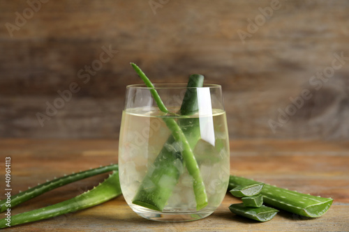 Fresh aloe drink with leaves in glass on wooden table
