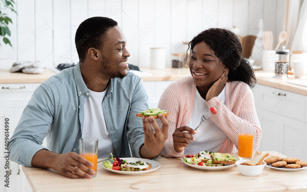 Positive Black Spouses Eating Tasty Breakfast And Drinking Orange Juice In Kitchen