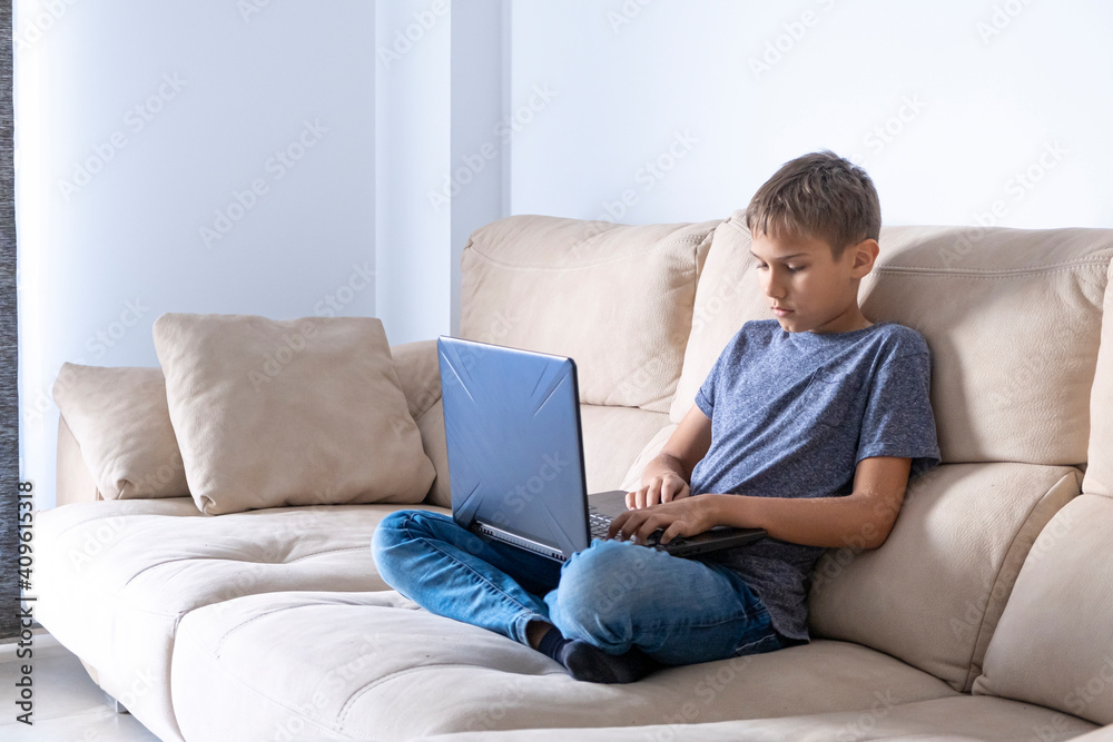 Boy doing homework task with laptop computer, watching video at home. Technology, education, online remote learning for kids. Stay at home entertainment Boy doing homework task with laptop computer, watching video at home. Technology, education, online remote learning for kids. Stay at home entertainment