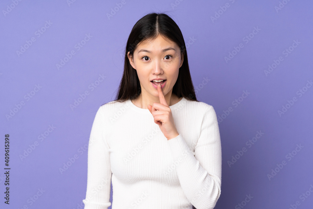 Young asian woman isolated on purple background showing a sign of silence gesture putting finger in mouth