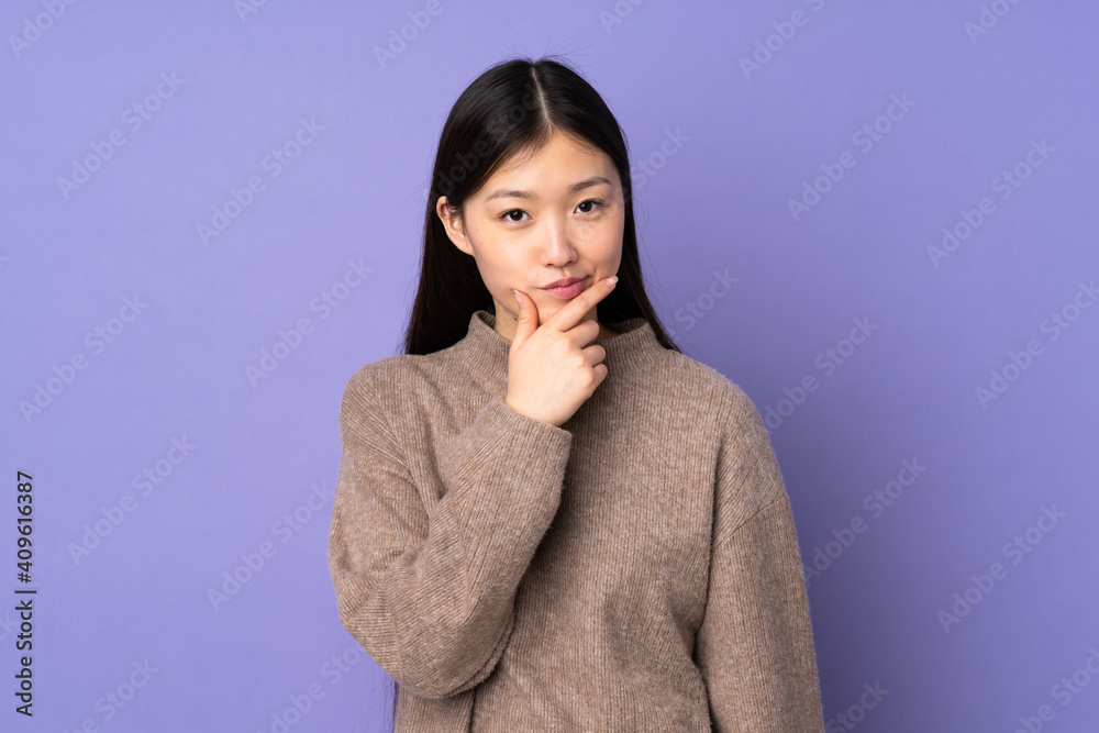 Young asian woman isolated on purple background thinking
