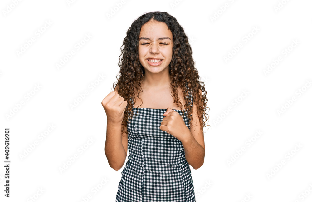 Teenager hispanic girl wearing casual clothes very happy and excited doing winner gesture with arms raised, smiling and screaming for success. celebration concept. Teenager hispanic girl wearing casual clothes very happy and excited doing winner gesture with arms raised, smiling and screaming for success. celebration concept.