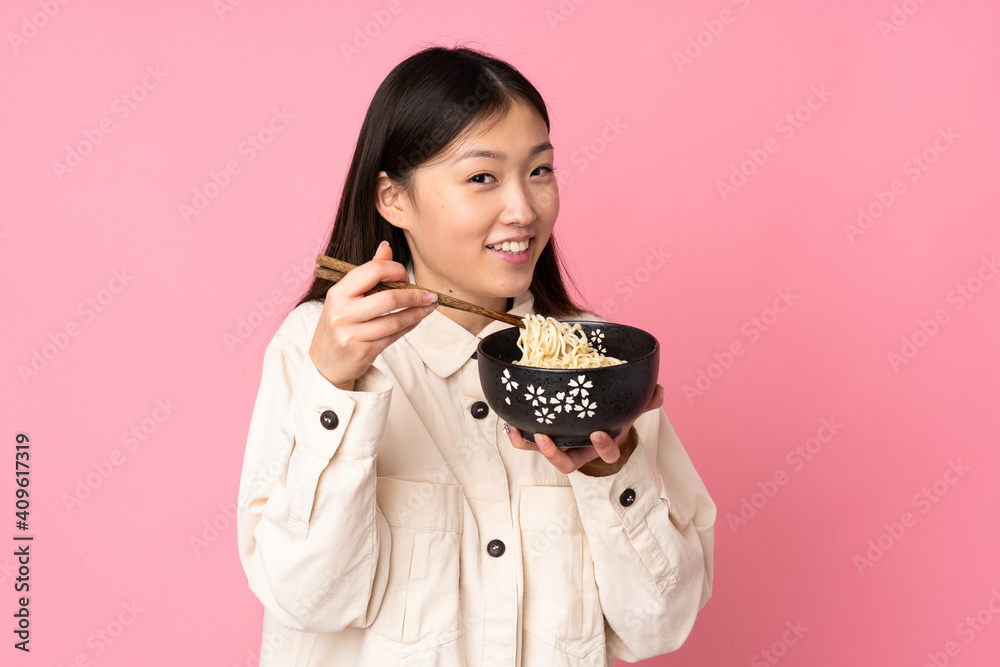 Young asian woman isolated on pink background holding a bowl of noodles with chopsticks Young asian woman isolated on pink background holding a bowl of noodles with chopsticks