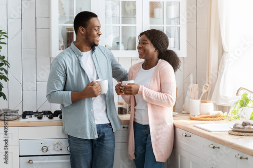 Black Millennial Couple Spending Time In Kitchen Together, Drinking Coffee And Chatting