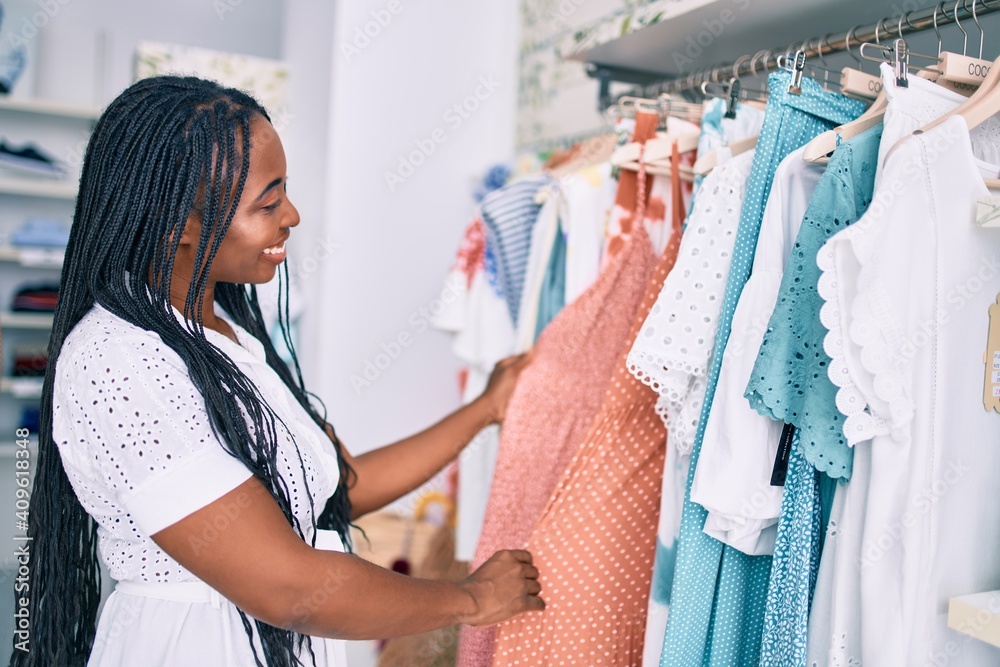 Young african american woman smiling happy holding clothes at clothing store Young african american woman smiling happy holding clothes at clothing store