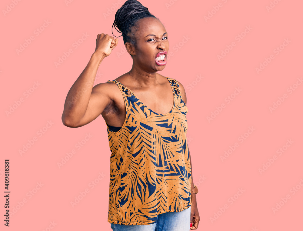 Young african american woman wearing casual clothes angry and mad raising fist frustrated and furious while shouting with anger. rage and aggressive concept.