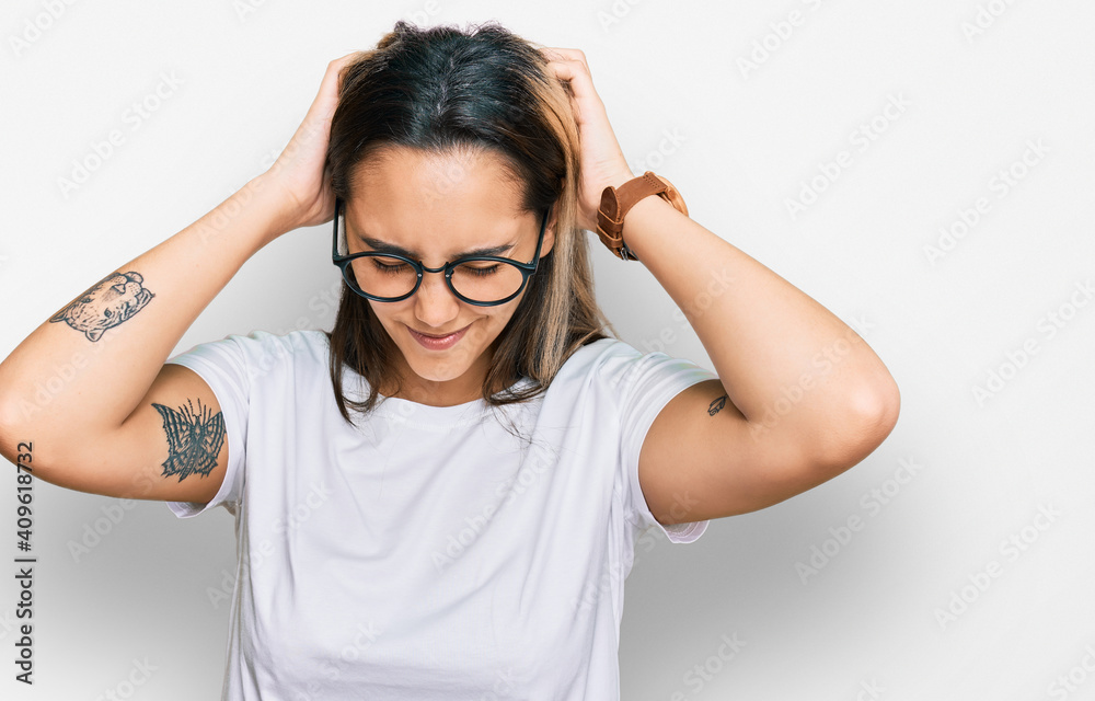 Young hispanic woman wearing casual white t shirt suffering from headache desperate and stressed because pain and migraine. hands on head. Young hispanic woman wearing casual white t shirt suffering from headache desperate and stressed because pain and migraine. hands on head.