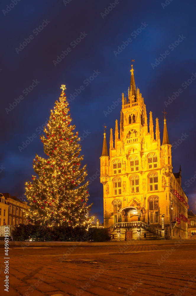 Gouda, The Netherlands, December 30, 2020 the market square in the holiday season, with a large Christmas tree next to the illuminated historic town hall