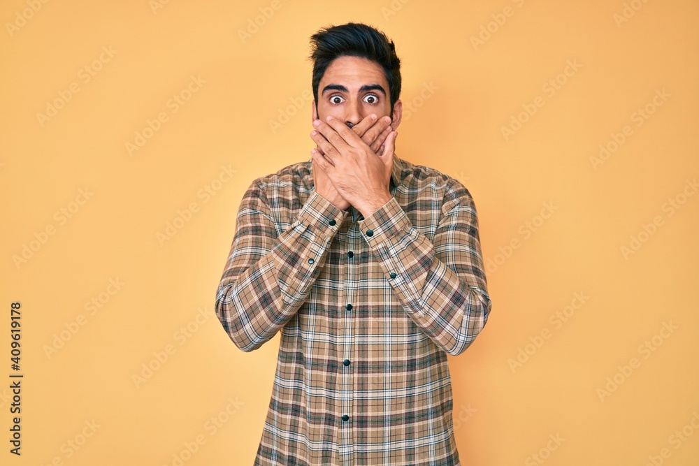 Handsome hispanic man with beard wearing casual clothes shocked covering mouth with hands for mistake. secret concept.