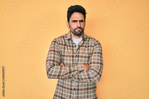 Handsome hispanic man with beard wearing casual clothes skeptic and nervous, disapproving expression on face with crossed arms. negative person.